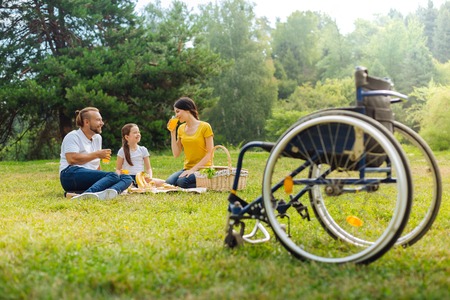 Family of a disabled man drinking juice in the meadowの写真素材