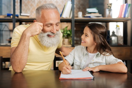 Loving grandfather having a look at his granddaughters homeworkの写真素材