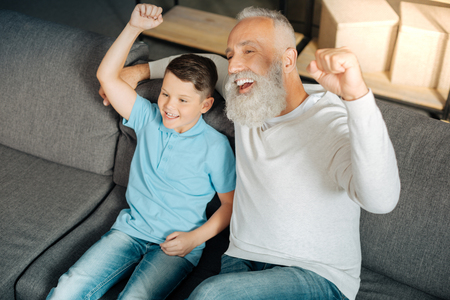 Little boy and his grandfather celebrating victory of favorite teamの写真素材