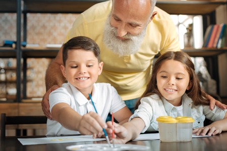 Grandfather watching adorable little siblings choose watercolorsの写真素材