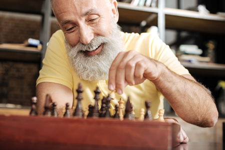 Upbeat senior man playing chess at homeの写真素材