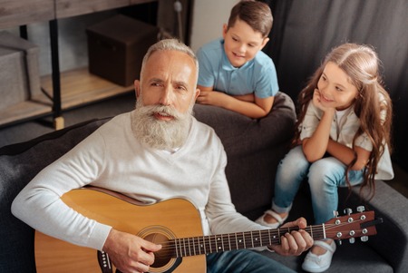 Inspired senior man playing guitar for his grandchildrenの写真素材