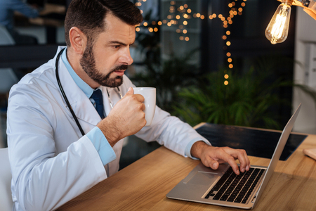 Nice thoughtful doctor holding a cup with teaの写真素材