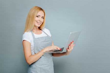 Positive delighted blonde holding laptopの写真素材