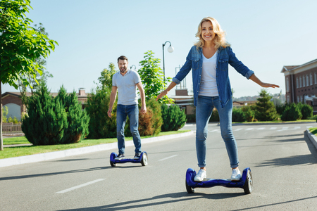 Happy husband and wife riding self-balancing scooters