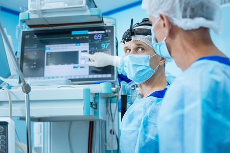 Serious assistant looking at his operation teacherの写真素材