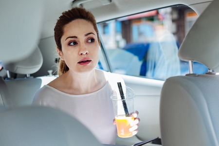 Positive young businesswoman holding a cup with juiceの写真素材