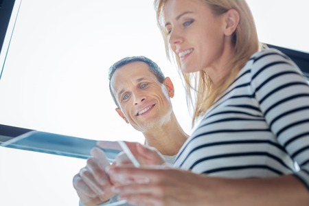 Cheerful positive colleagues using electronic device