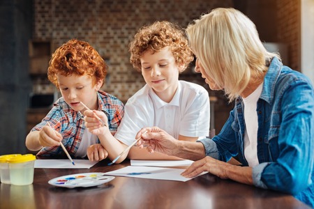 Concentrated brothers painting with granny at home