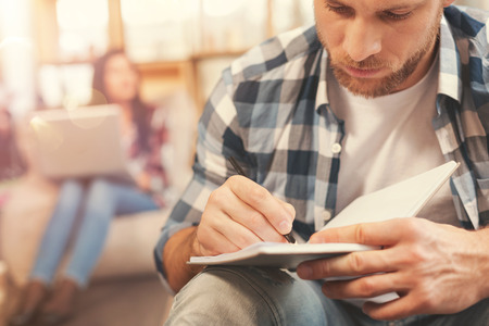 Scaled up look on serious guy making notesの写真素材