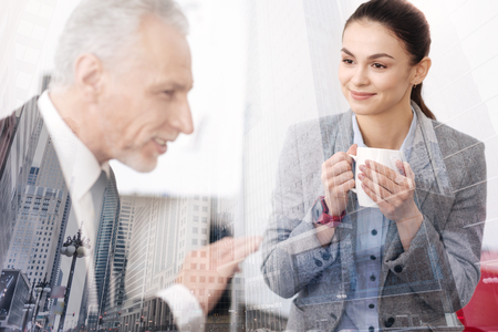 Positive businesswoman drinking coffee with her adult colleagueの写真素材