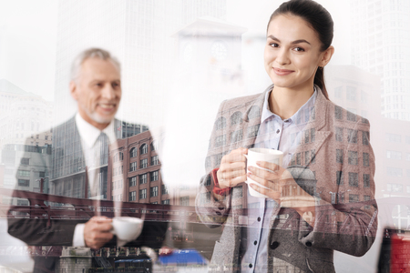Cheerful beautiful businesswoman drinking tea with her colleagueの写真素材