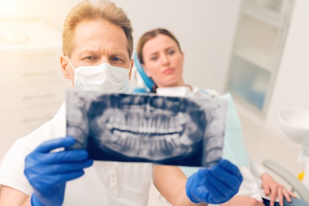 Serious mature doctor examining x ray jaws scanの写真素材