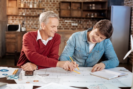 Smiling man pointing at problematic place in colleagues blueprintの写真素材