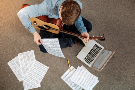 Top view of young man reading musical notationの写真素材