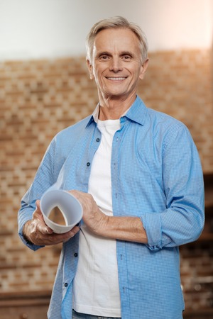 Joyful senior engineer smiling and holding blueprintの写真素材