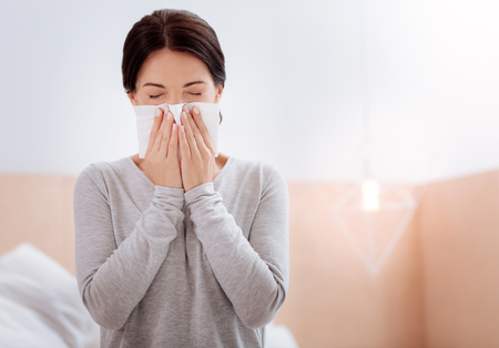 Allergic woman pressing a napkin to her noseの写真素材