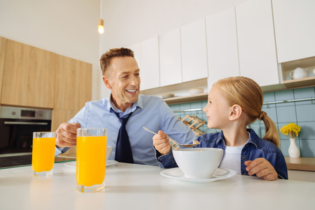 Joyful nice man having breakfast with his daughterの写真素材