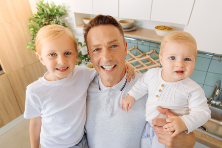 Delighted nice man holding his daughtersの写真素材