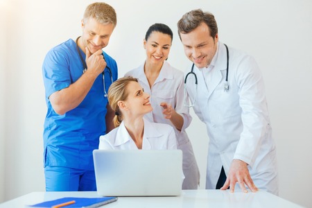 Cheerful doctors using laptop together at workの写真素材