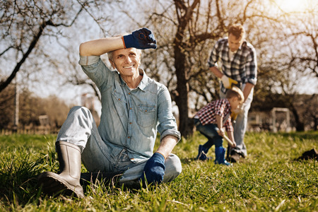 Positive delighted pensioner sitting on the grassの写真素材