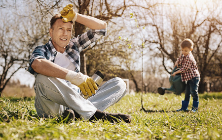 Tired gardener crossing legs while sitting on grassの写真素材