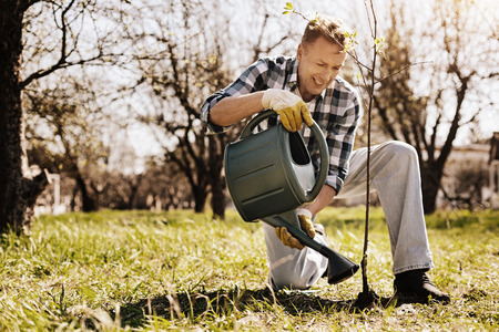 Positive delighted man watering his plant