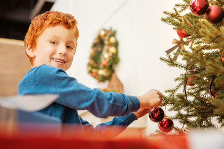 Smiling little child decorating tree for christmasの写真素材