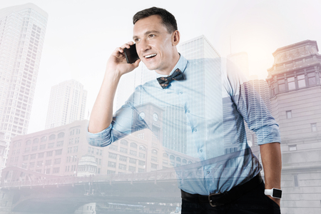 Pleasant delighted man enjoying his phone conversationの写真素材