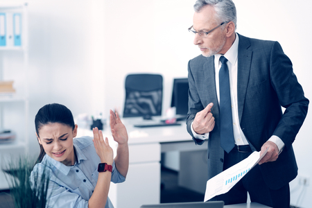 Angry mature boss shouting at stressed employeeの写真素材