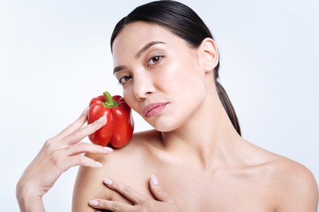 Charming brunette holding bell pepper on shoulderの写真素材