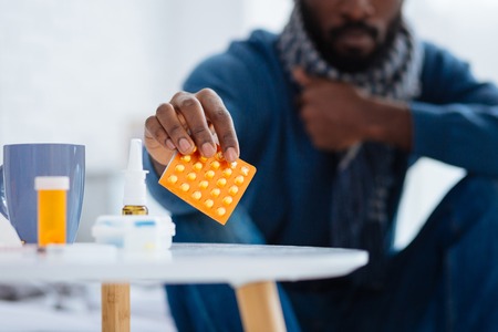 Young ill person leaving his pills on the tableの写真素材
