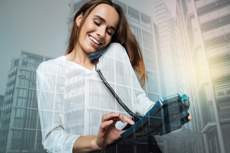 Cheerful nice woman dialing a phone number