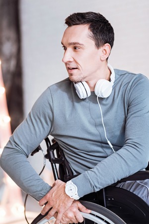 Waiting for result. Disabled young man opening mouth and holding hands together on the wheel while having ideaの写真素材