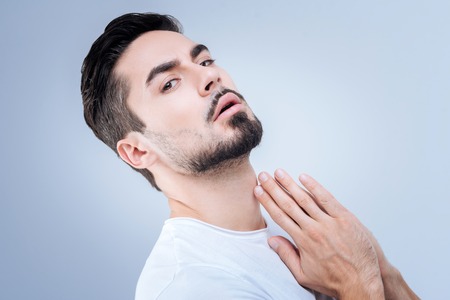 Leaning back. Smart emotional bearded man feeling confident while leaning back with his hands being closeの写真素材