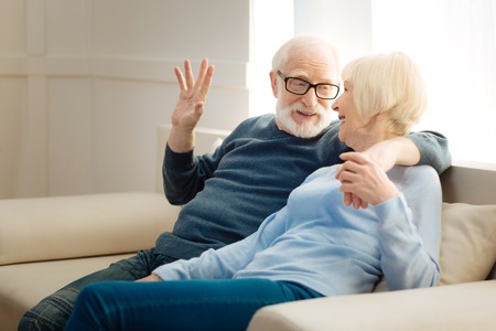 Let it be. Handsome male person keeping smile on his face and turning his head while embracing wife
