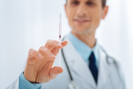 Let me check. Attentive medical worker wearing uniform and preparing instrument for injectionの写真素材