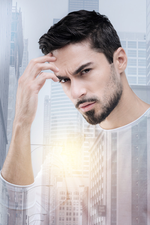 Facial expressions. Attentive male person wrinkling forehead and bowing head while having some thoughtsの写真素材