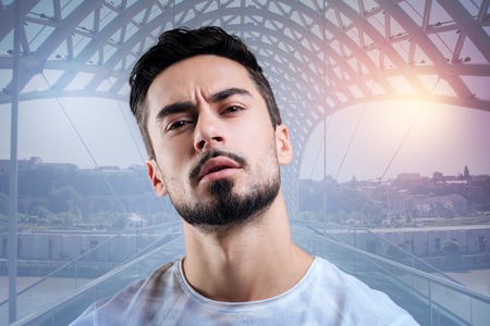 Very attentive. Attentive concentrated educated man looking interested while being in a modern art gallery and observing beautiful picturesの写真素材