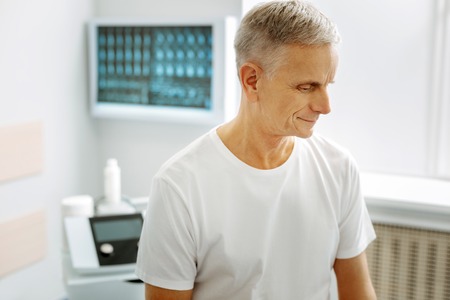 Professional medical help. Nice pleasant aged man being in the doctors office and waiting for the therapist while visiting a hospitalの写真素材