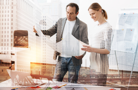 Results of our work. Professional colleagues engineers holding a blueprint while standing in the officeの写真素材