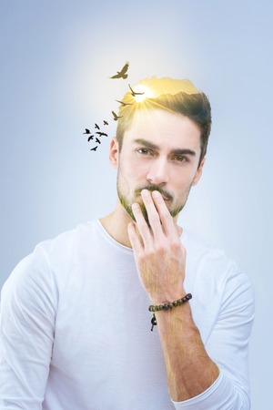 Absolute freedom. Handsome pleasant good looking man touching his lips and thinking about birds in...