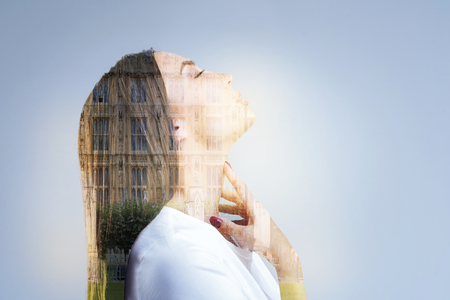 Architecture inspires. Pensive creative young woman dreaming  in profile  and caressing her neck while closing her eyesの写真素材