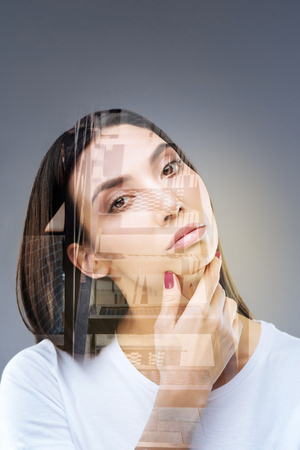 Multiple choices. Inspired focused nice woman estimating variants  and looking at the camera while caressing her faceの写真素材