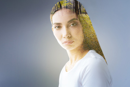 Charming autumn. Appealing elegant smart woman posing on the grey background while reflecting and returning to nature inspirationの写真素材