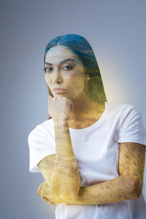 Next step. Serious musing charming woman gazing at the camera  and putting head on the fist while estimating chancesの写真素材