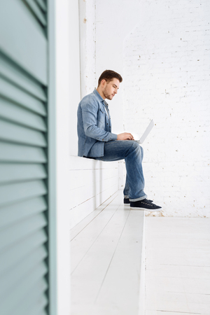 Do it quickly. Concentrated male person bowing head and looking at screen of computer, typing messageの写真素材