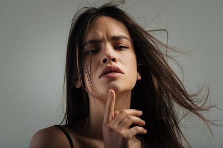 Thoughts. Beautiful meditative dark-haired young woman thinking and staring and touching her chinの写真素材
