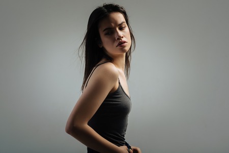 Beauty. Attractive stony-faced dark-haired young woman looking over her shoulder and thinking and wearing a topの写真素材