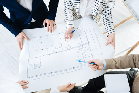 Impressive blueprint.  Young female and male hands carrying blueprint and holding pensの写真素材